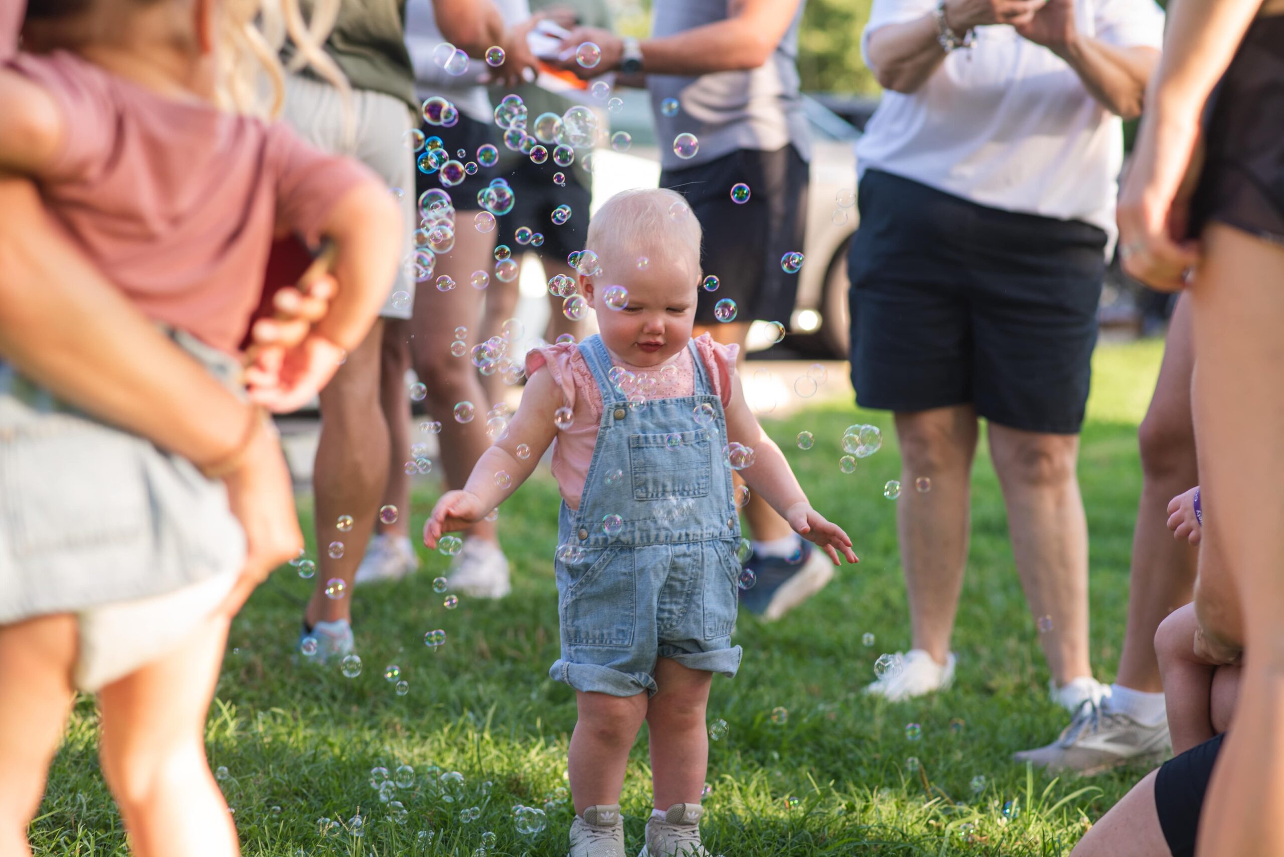 toddler in overalls plays with bubbles