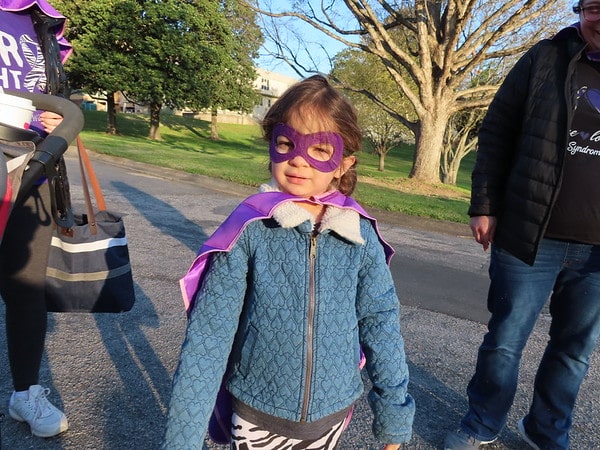 Young girl in a superhero mask and cape at MPS awareness event