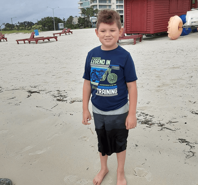 Boy with MPS VI in swim trunks at the beach
