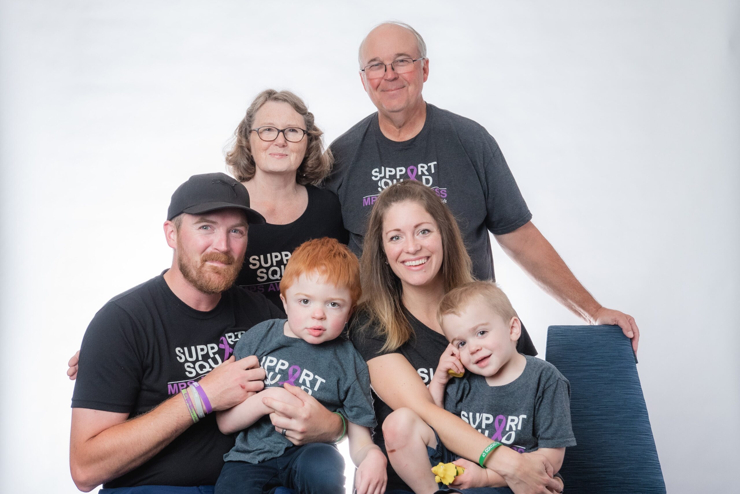 Three generations of family smiling in matching MPS awareness tshirts