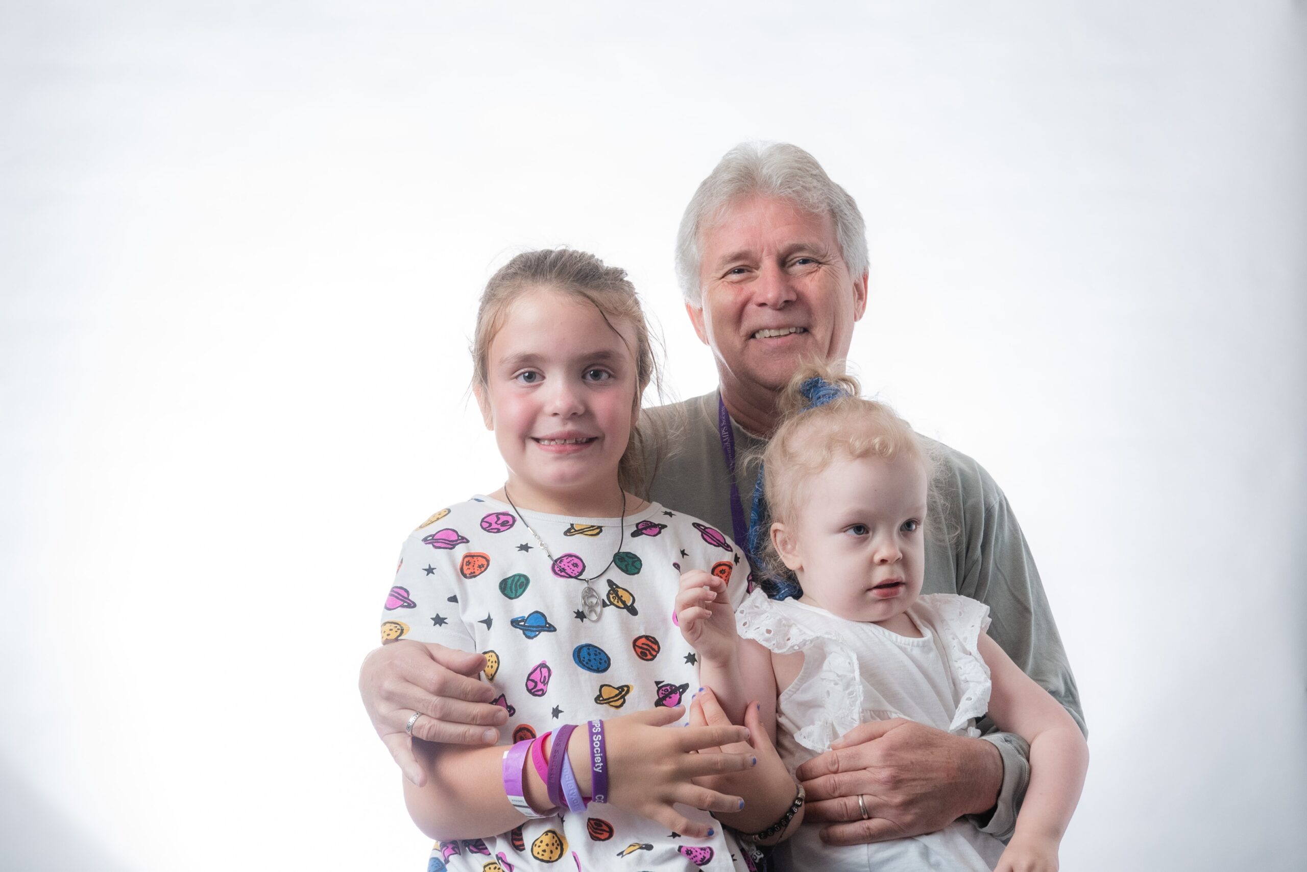 Family of 3 poses for a portrait against a white backdrop