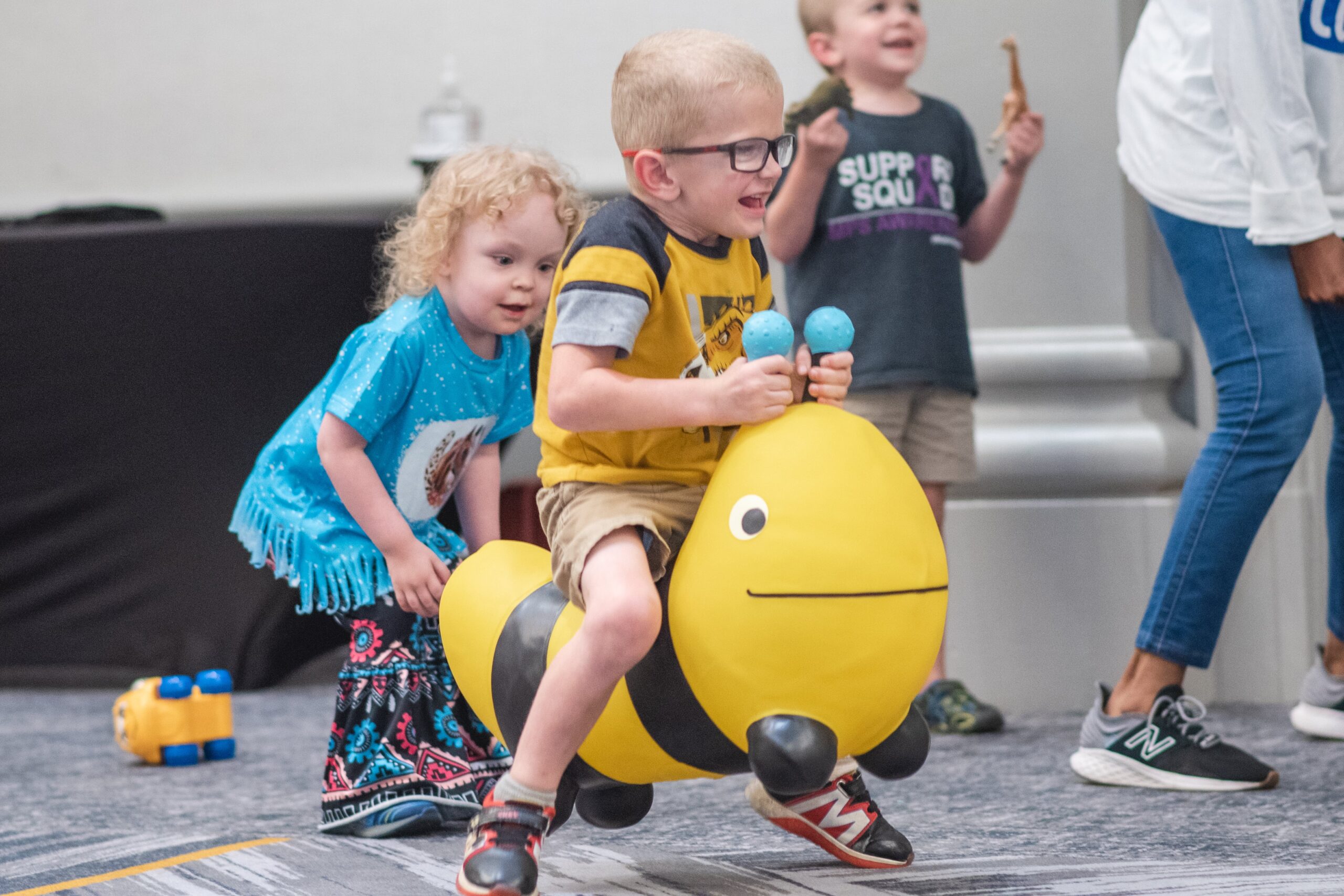 boy with glasses riding a bee-shaped big wheel toy