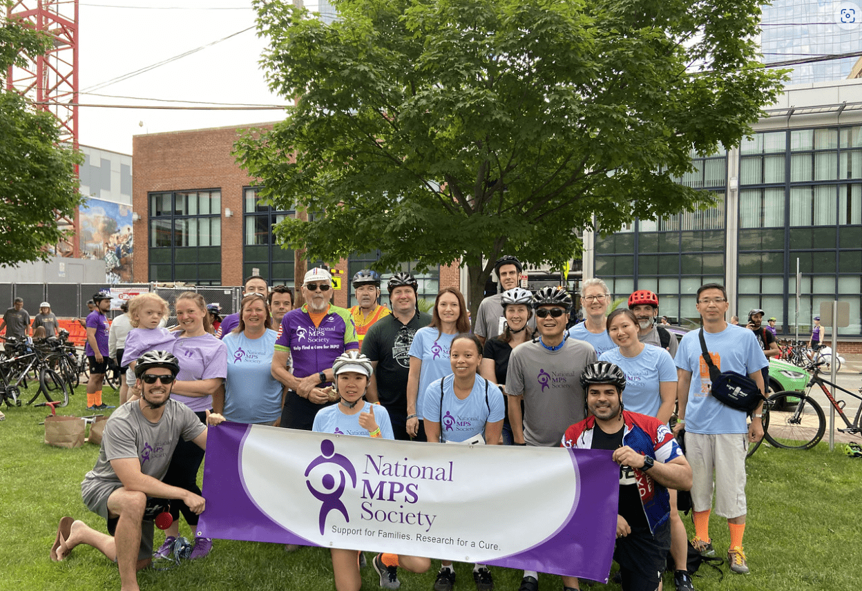 cyclists pose with the banner for an MPS fundraising event